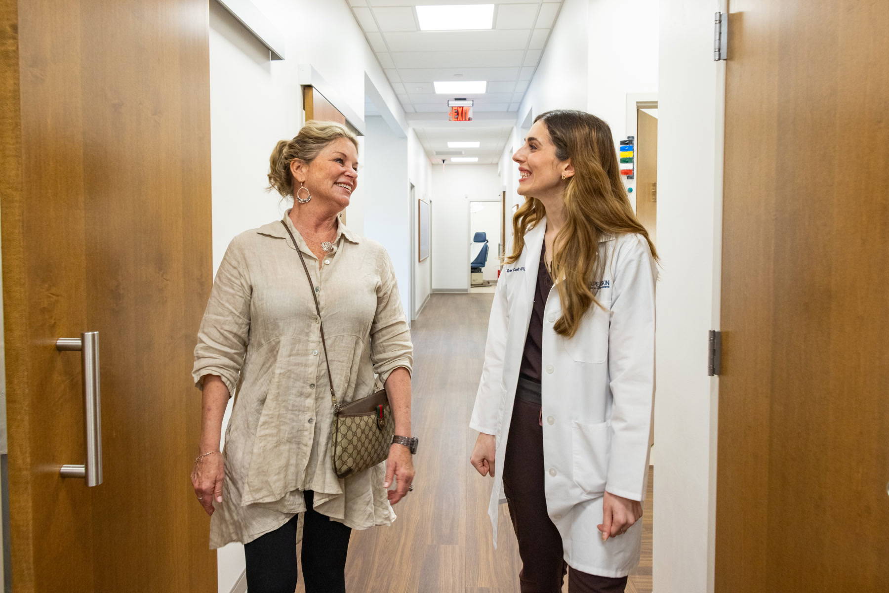 Apex Skin provider laughing with a patient in the hallway Apex Skin provider laughing with a patient in the hallway